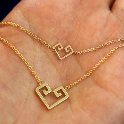 A Geometric heart bracelet and large necklace layered on a model's palm