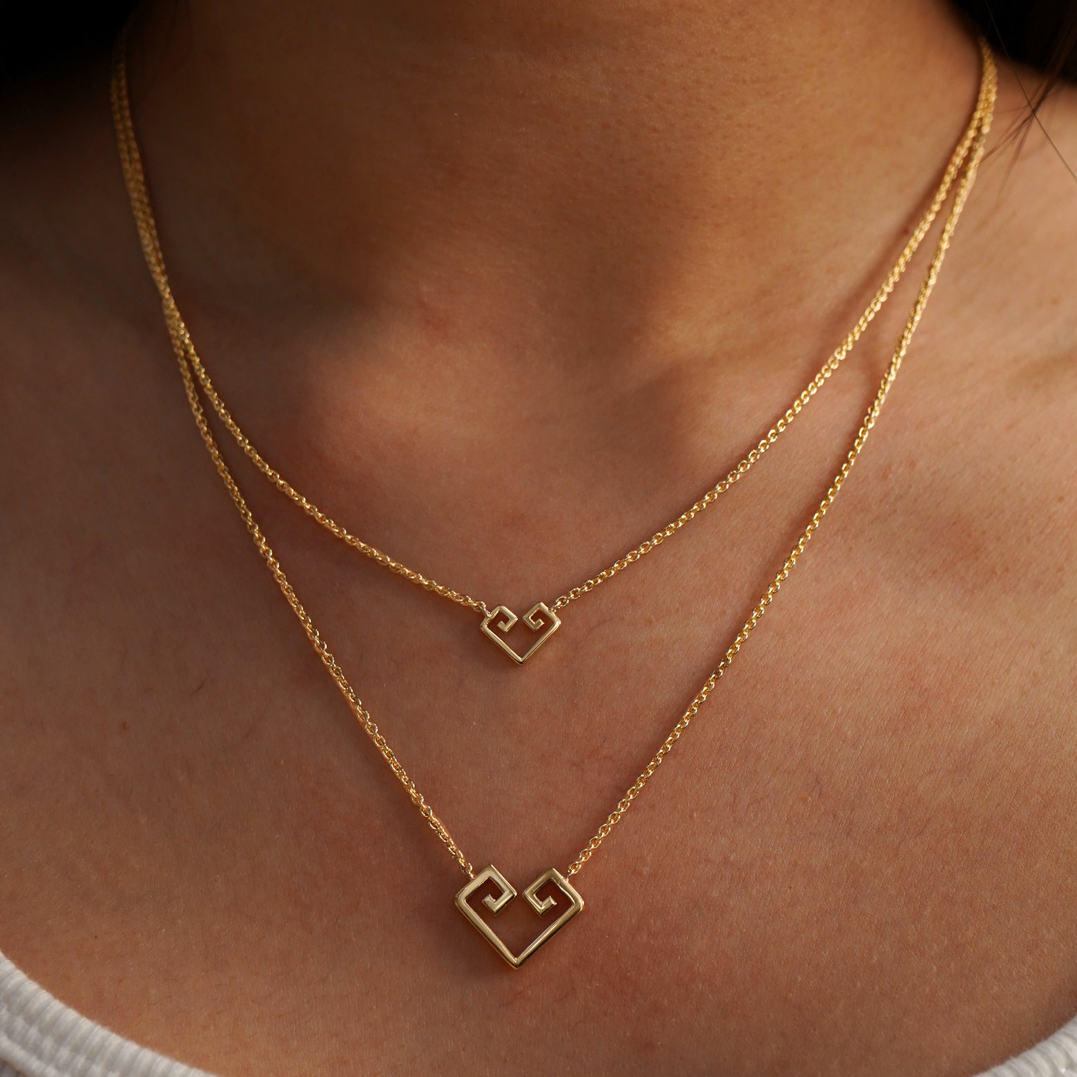 A model wearing a Small Chere Heart Necklace and a Large Chere Heart Necklace layered
