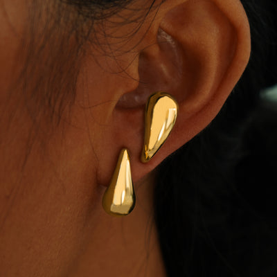 A model's ear wearing two yellow gold Teardrop Puffy Earrings, one on their lobe and one on in an antitragus piercing