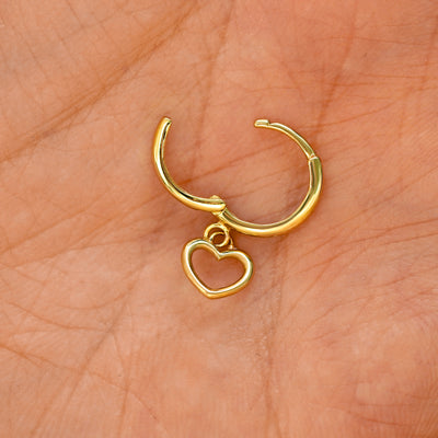 A solid 14k yellow gold Heart Dangle Huggie Hoop Earring open a model's palm