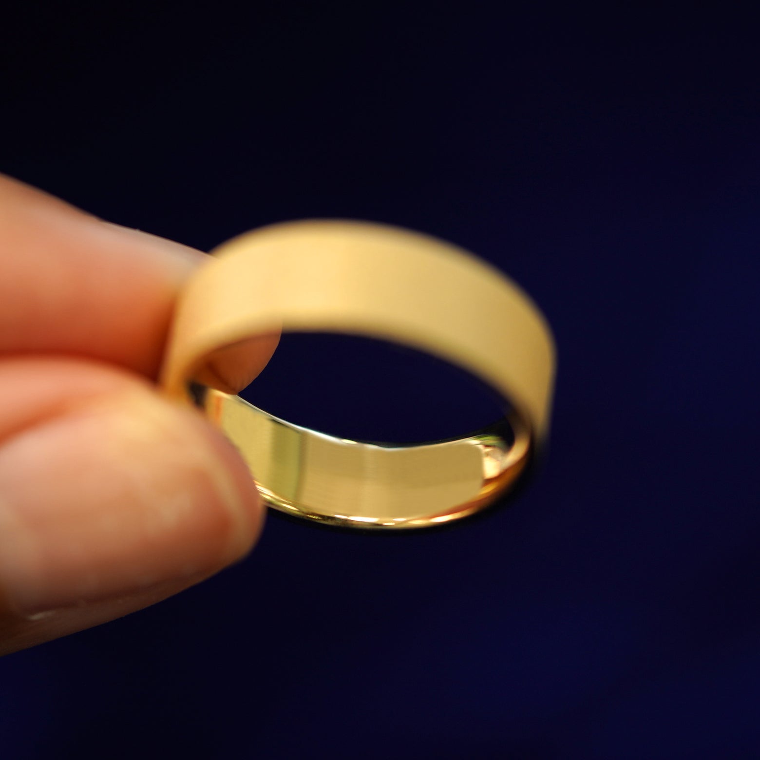 A model holding a Industrial Stardust Band tilted to show the inside of the ring