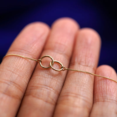 A yellow gold Mini Bound Together Bracelet resting on a model's fingers