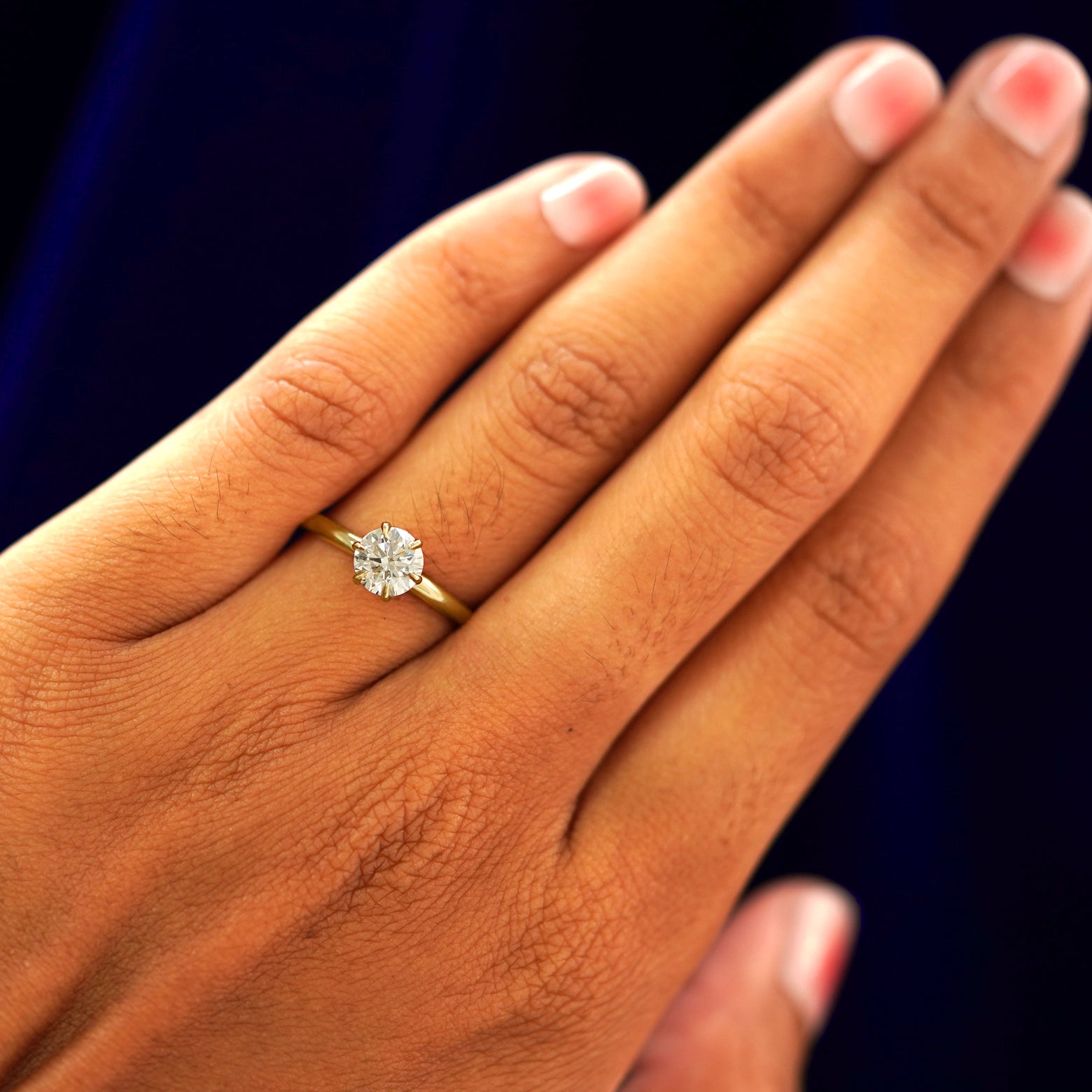 Close up view of a model's hand wearing a yellow gold Round Lab Diamond Ring