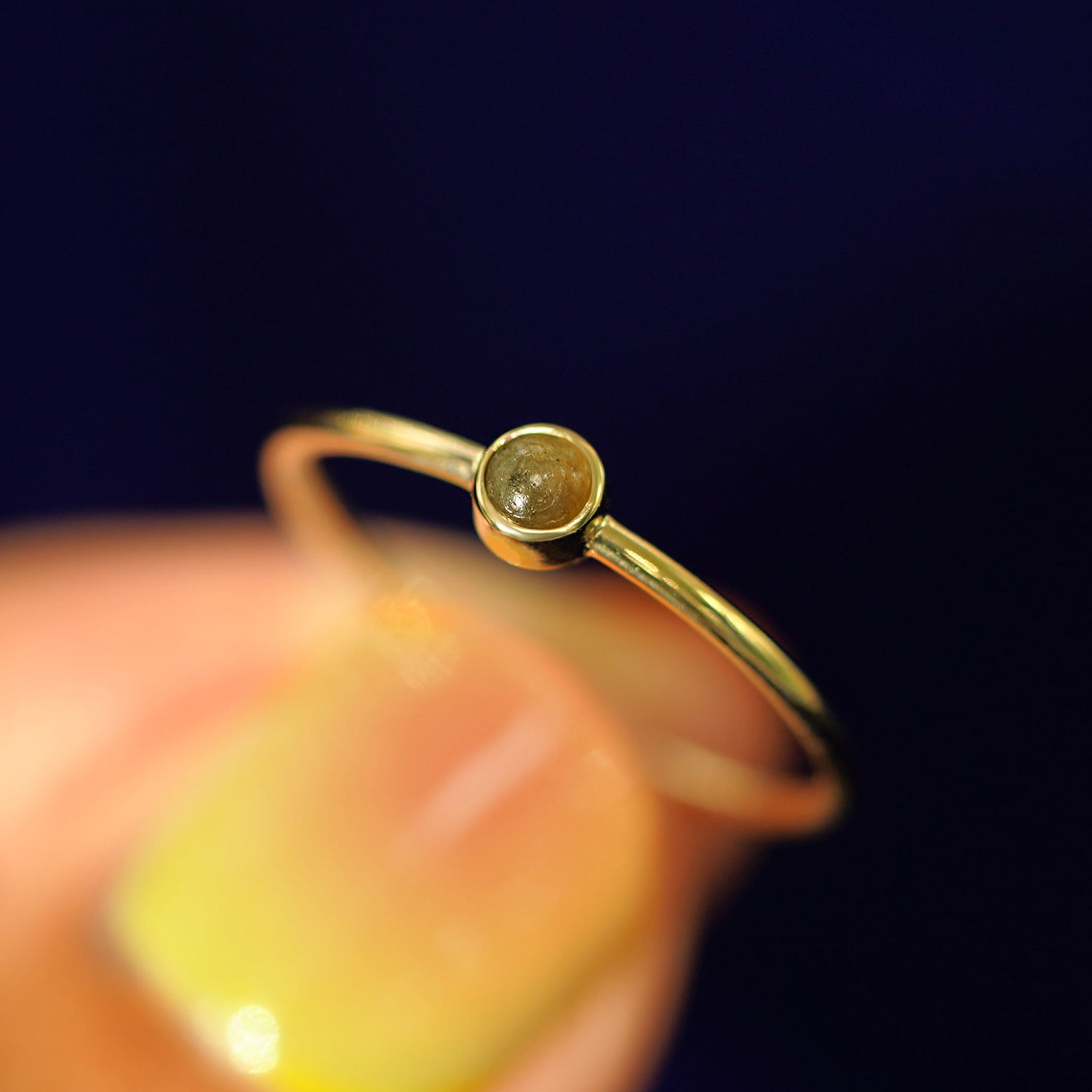 A model holding a Labradorite Ring tilted to show the details of the bezel setting