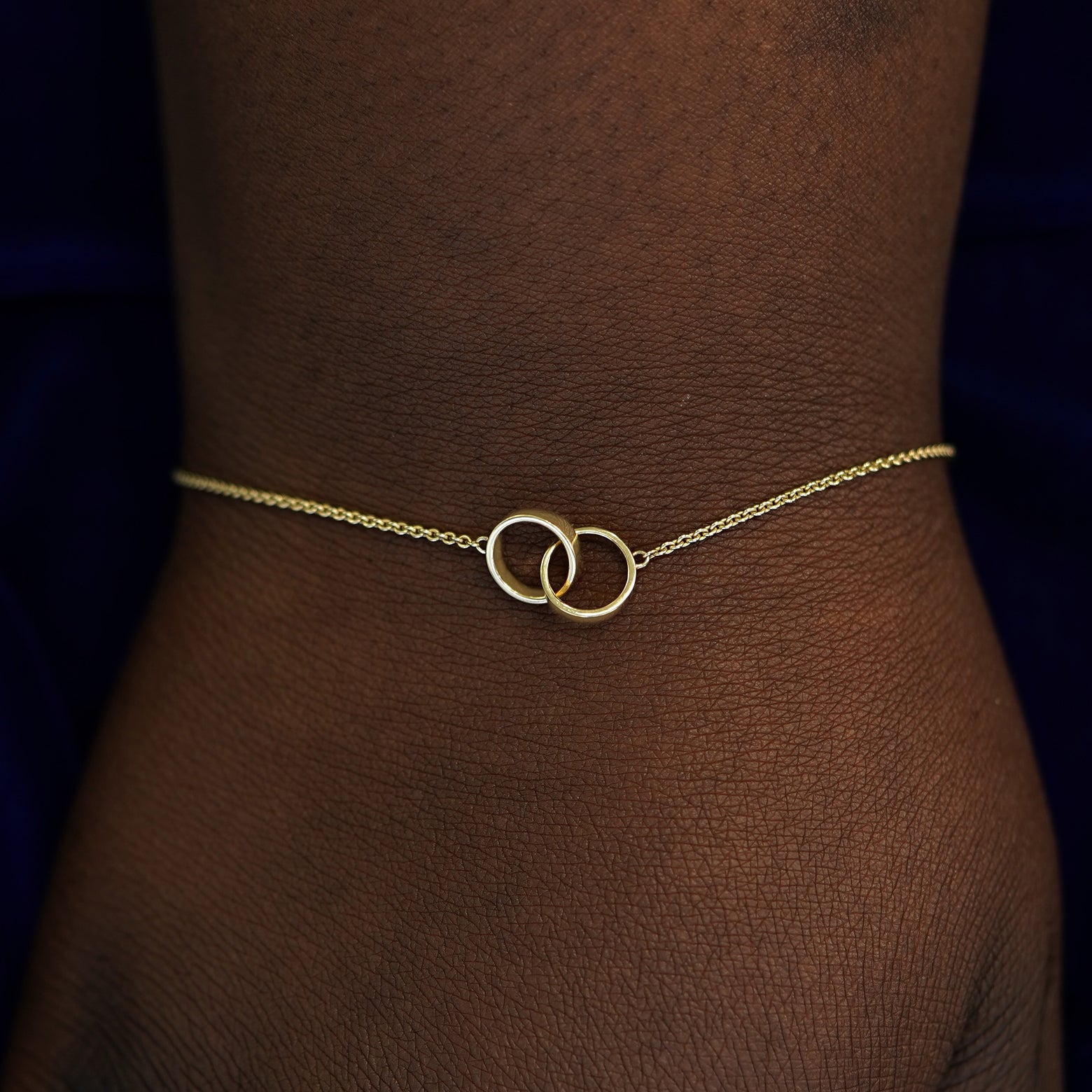 A model's wrist wearing a solid gold Bound Together Bracelet