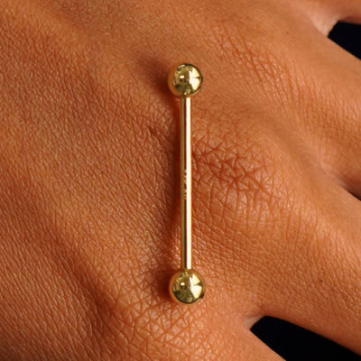 Close up view of a 14 karat gold Large Straight Barbell Piercing resting on the back of a model's hand