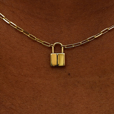 Close up view of a model's neck wearing a 14 karat gold lock necklace