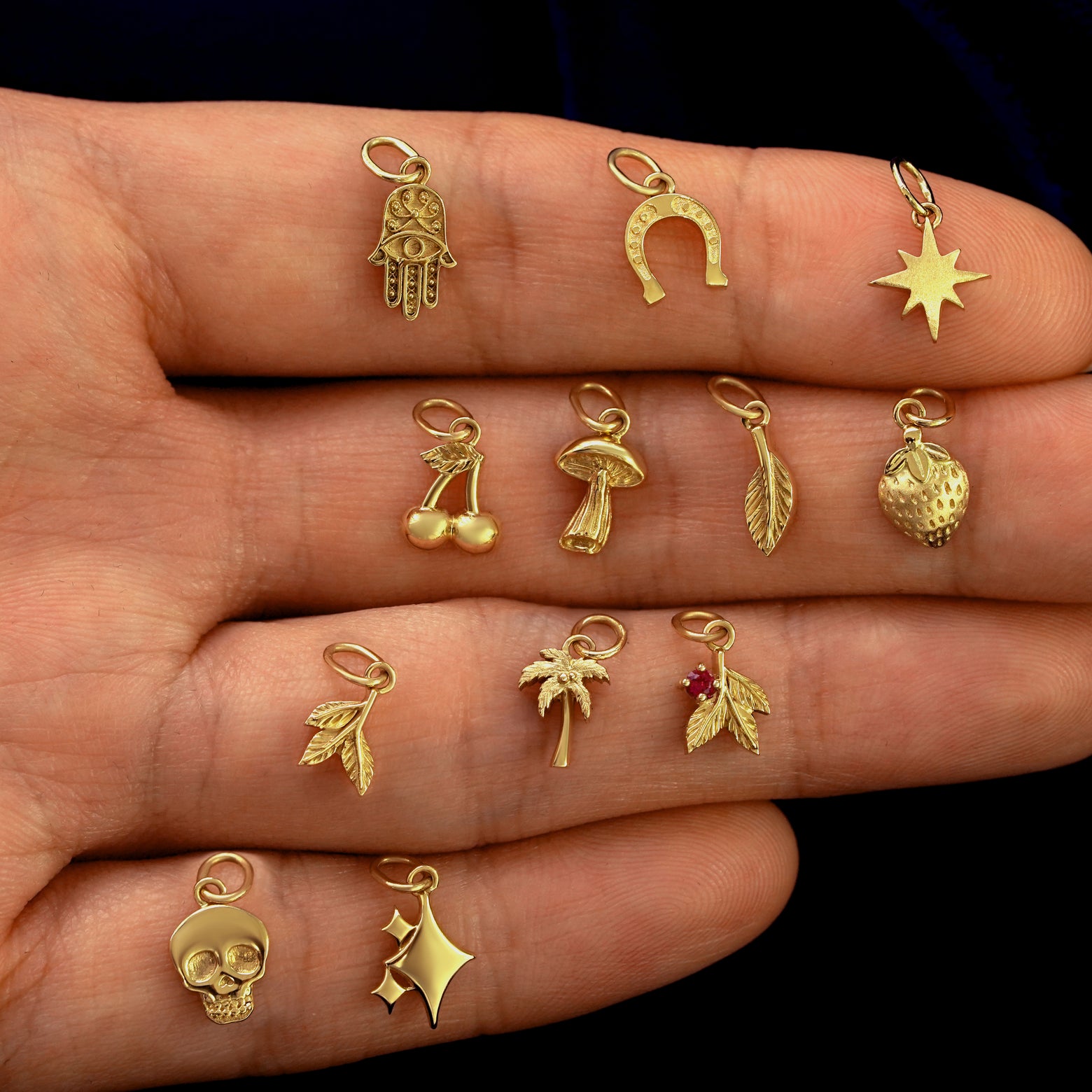 Close up view of a model's wrist wearing various good luck and nature themed 14k gold charms on a cable bracelet