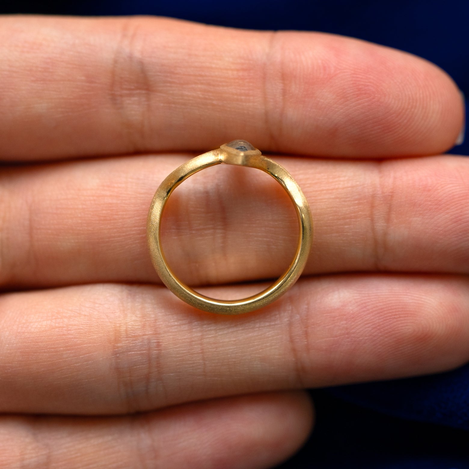 A yellow gold marquise salt and pepper diamond cabochon stardust ring in a model's hand showing the thickness of the band