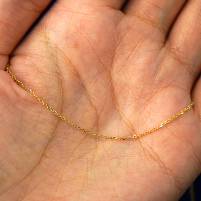 A yellow gold Medium Cable Chain draped on a model's palm