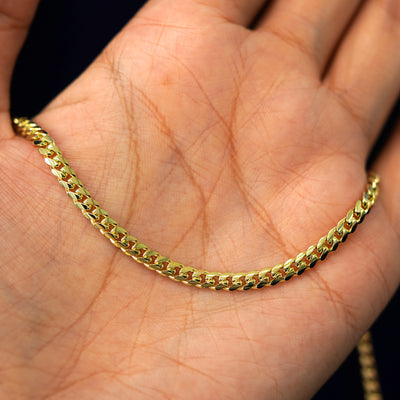 A yellow gold Medium Miami Chain draped on a model's palm