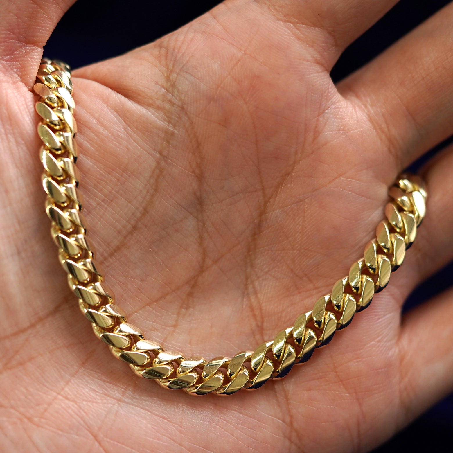 A yellow gold Miami Cuban Bracelet draped on a model's palm