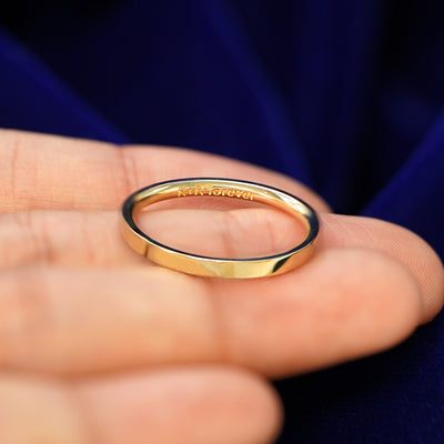 A Industrial Mirror Band in a model's hand tilted to show engraving on the inside of the band that reads K + R Forever