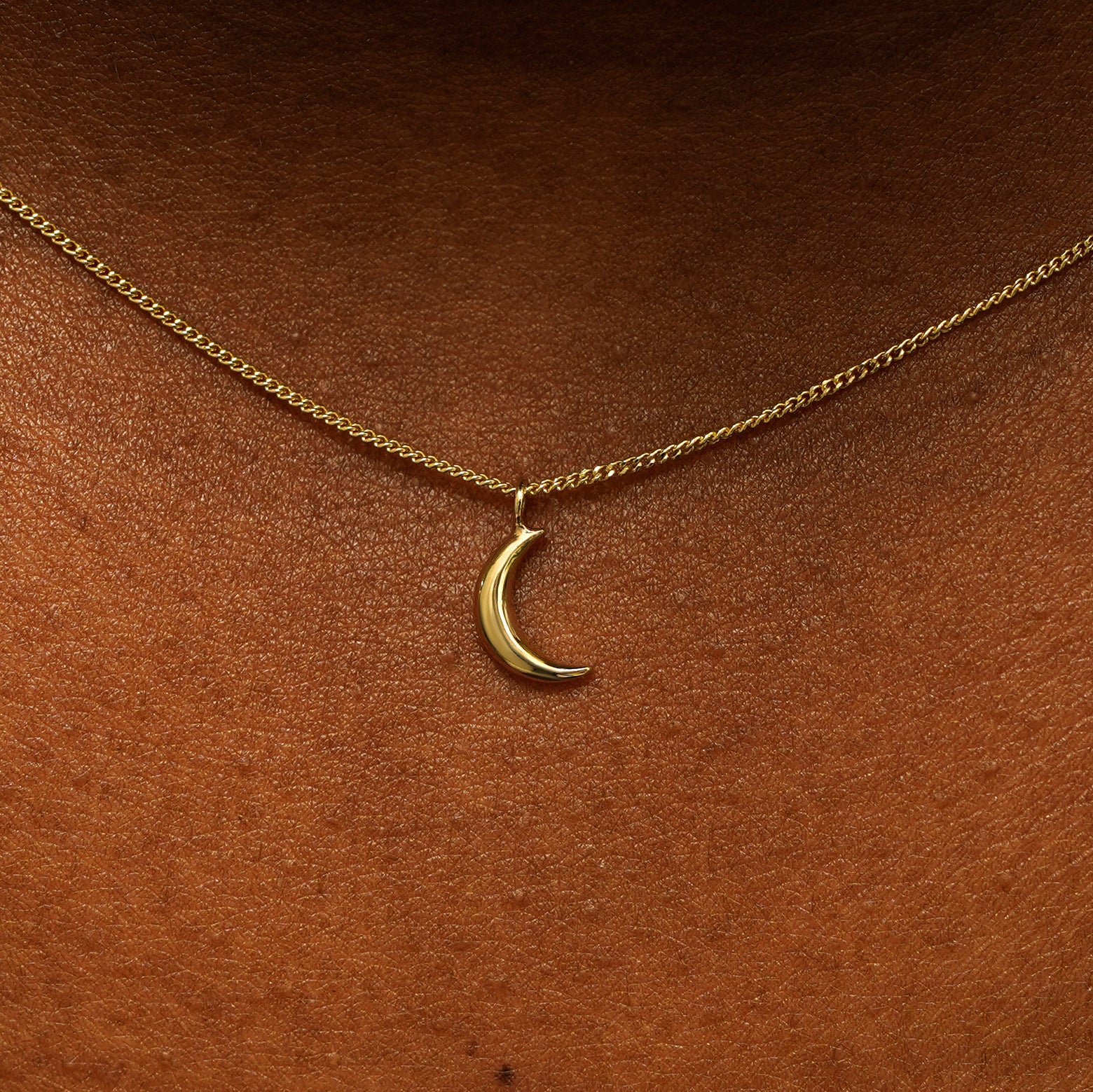 Close up view of a model's neck wearing a 14 karat gold crescent moon necklace