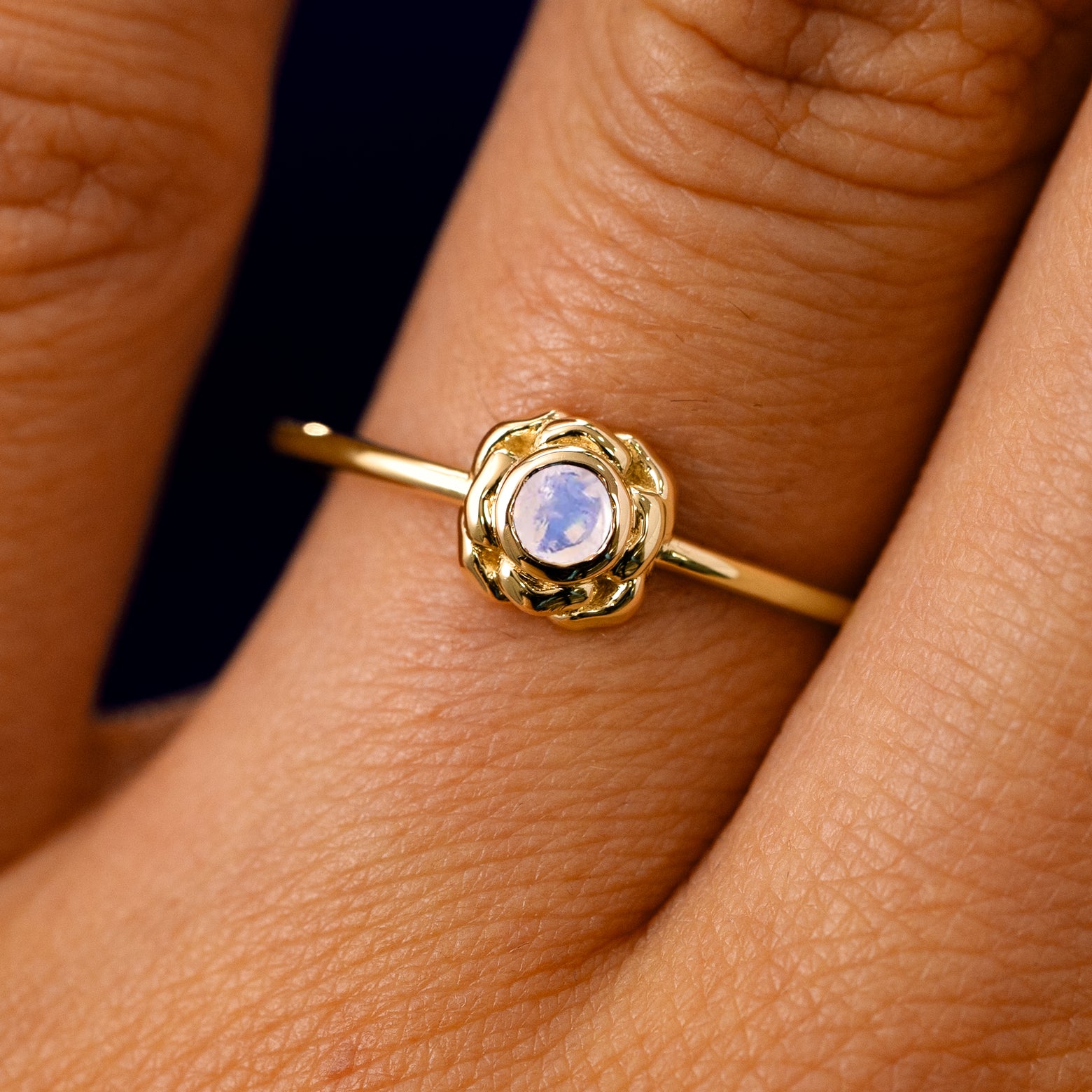 A solid 14k yellow gold Moonstone Gemstone Flower Ring on a model's finger