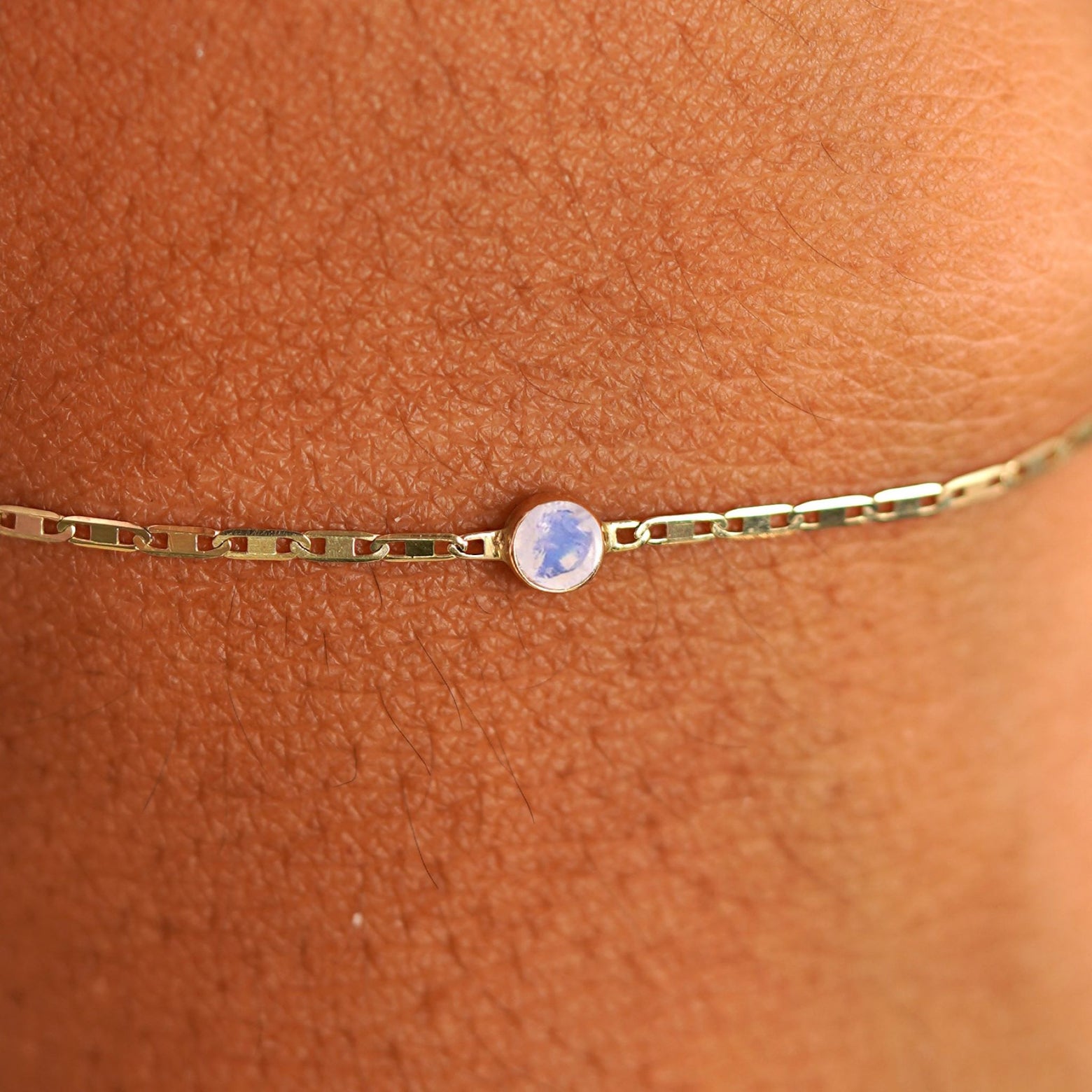 Close up view of a models wrist wearing 14k yellow gold Moonstone Bracelet