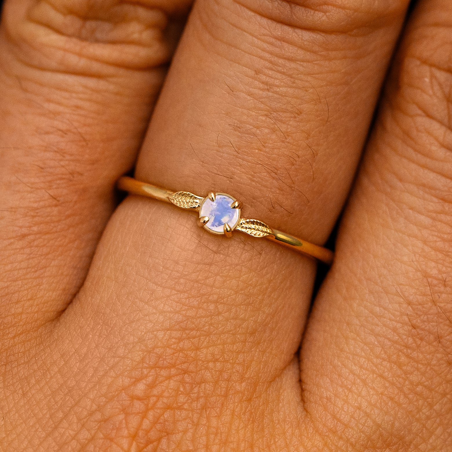 A solid 14k yellow gold Moonstone Gemstone Two Leaf Ring on a model's finger