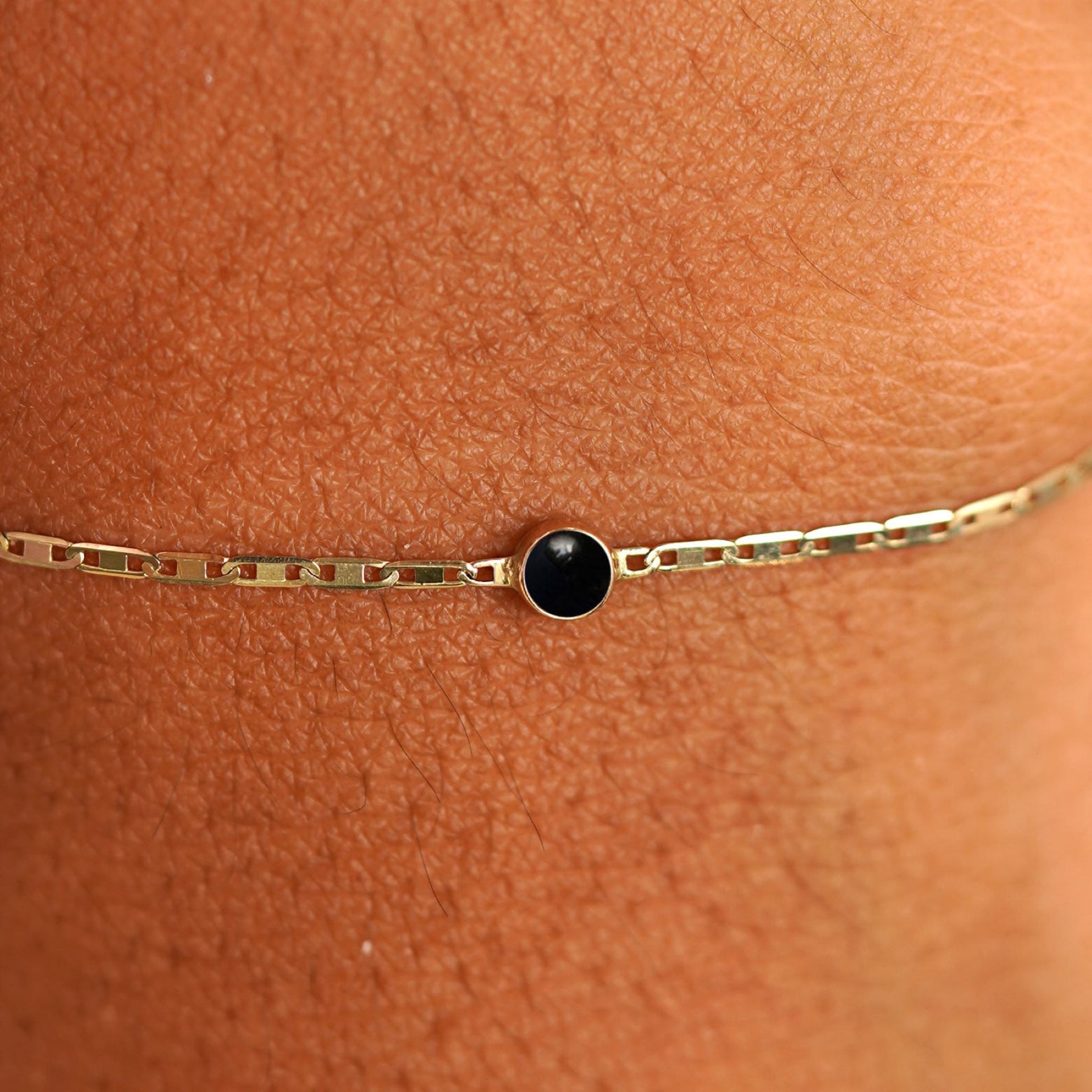 Close up view of a models wrist wearing 14k yellow gold Onyx Bracelet