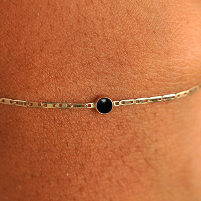 Close up view of a models wrist wearing 14k yellow gold Onyx Bracelet