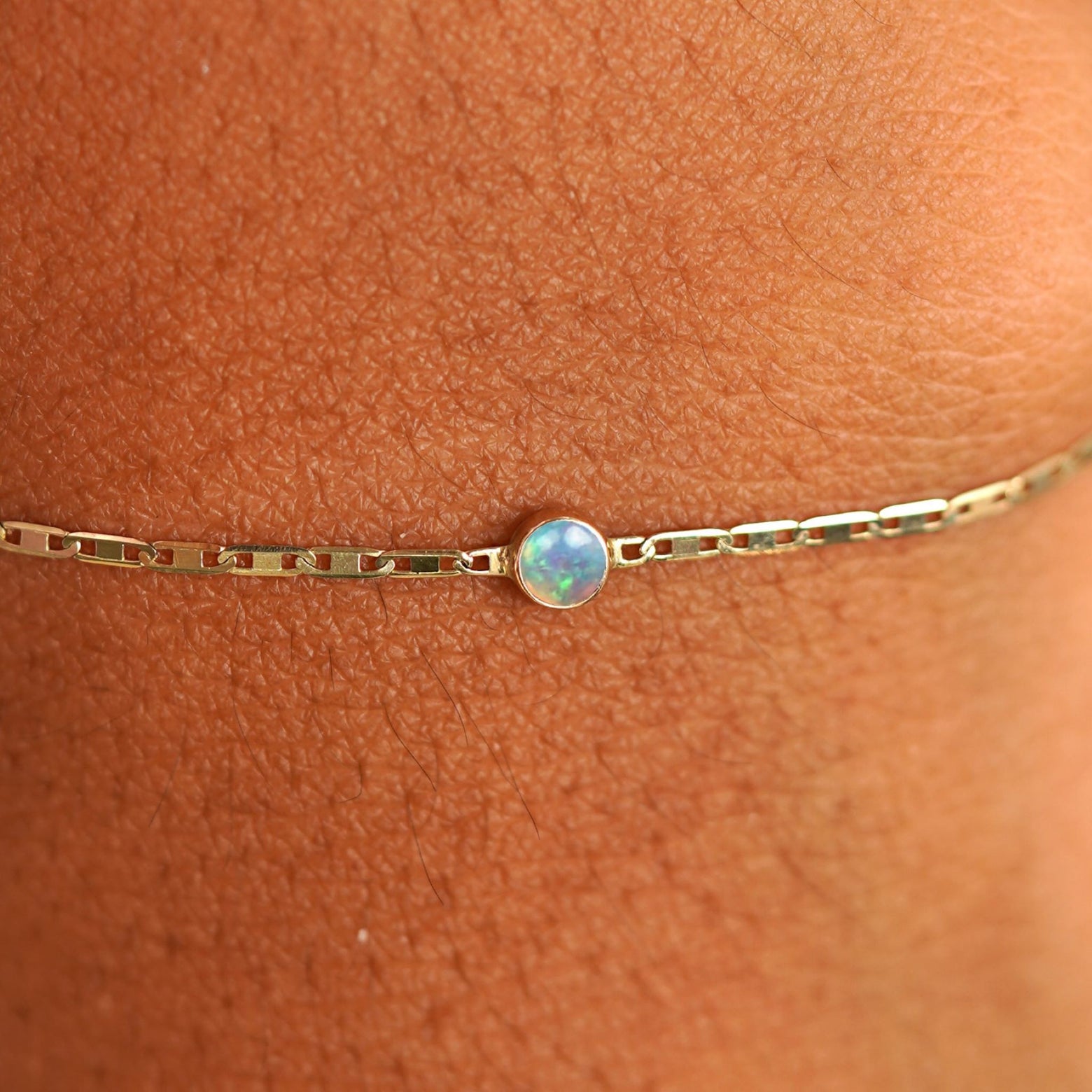 Close up view of a models wrist wearing 14k yellow gold Opal Bracelet