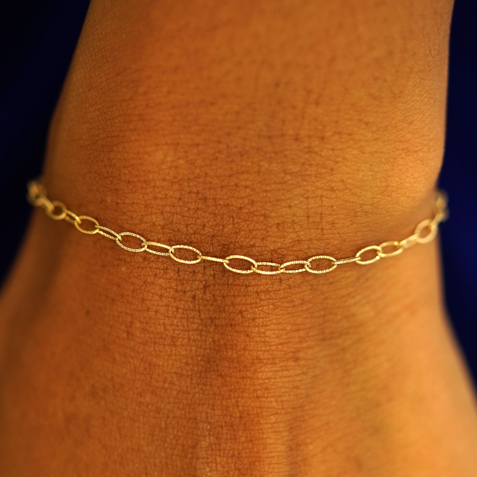 A model's wrist wearing a 14k yellow gold Veren Bracelet