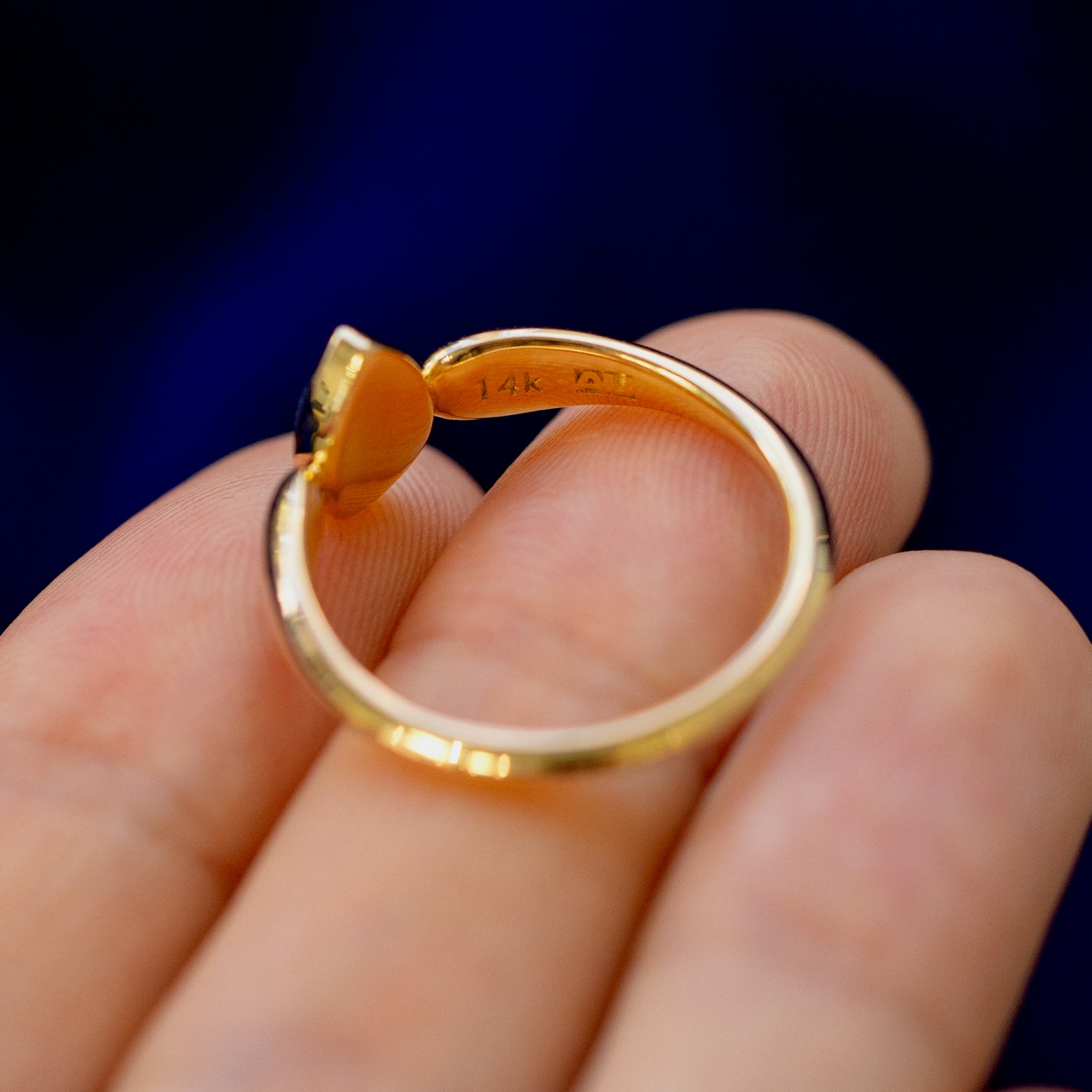 A solid gold pear cabochon salt and pepper diamond ring on a model's fingertips showing the inside of the band