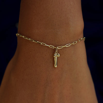 Close up view of a model's wrist wearing a yellow gold Penis Charm on a  Butch Bracelet