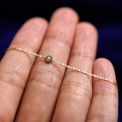 A yellow gold Peridot Bracelet resting on a model's fingers