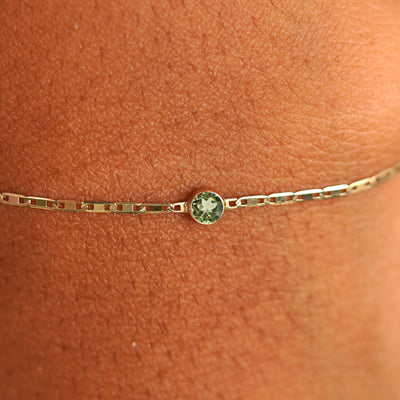 Close up view of a models wrist wearing 14k yellow gold Peridot Bracelet