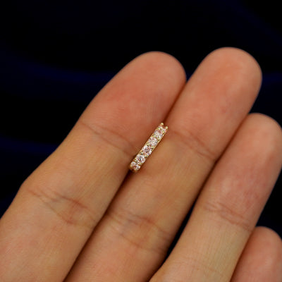 A small Pink Lab Diamond huggie hoop earring between a model's fingers to show the gems