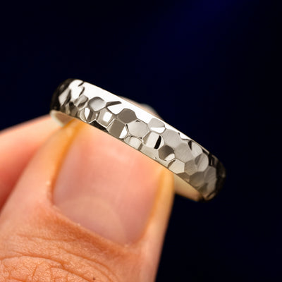 A model holding a Platinum Curvy Hammered Band tilted to show the details of the hammered finish