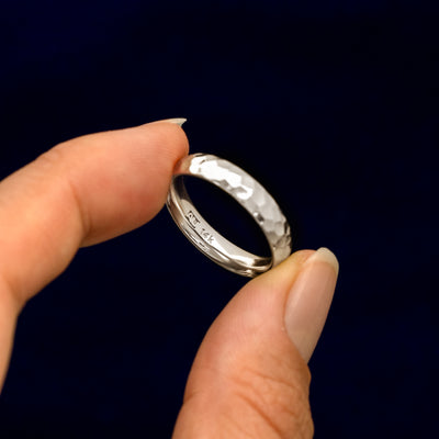 A model holding a Platinum Curvy Hammered Band tilted to show the inside of the band