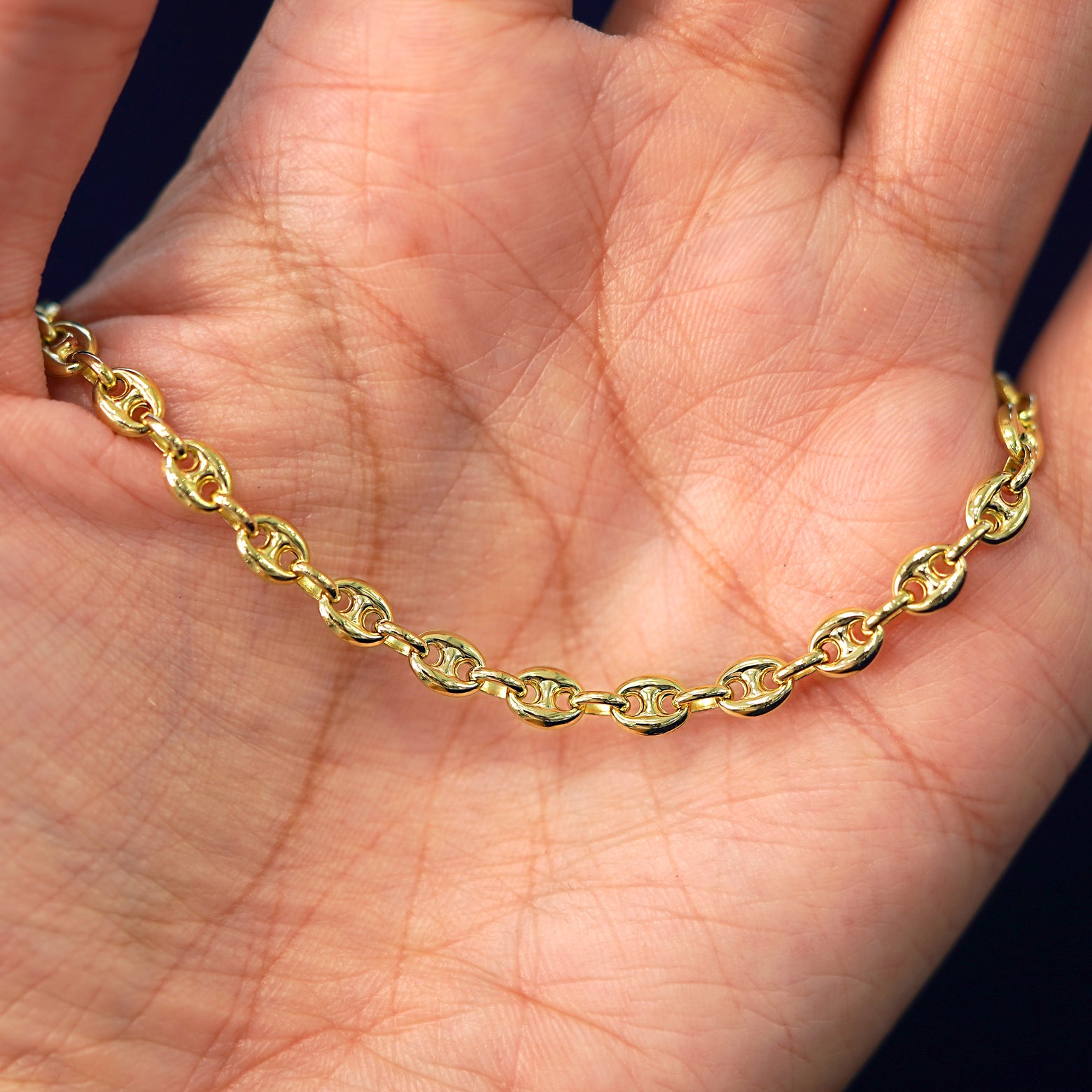 A yellow gold Puffy Mariner Bracelet draped on a model's palm