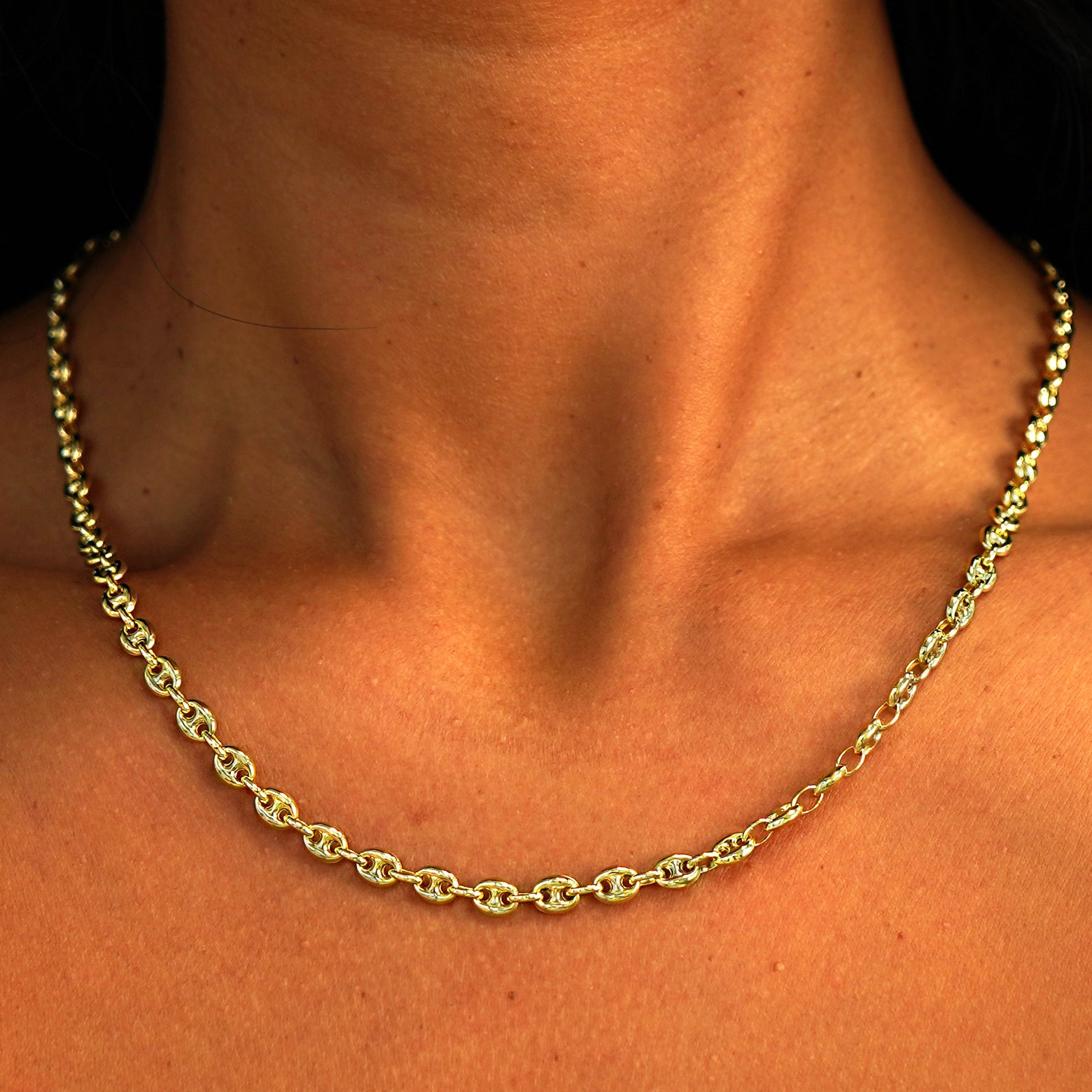 A model's neck wearing a solid 14k yellow gold Puffy Mariner Chain