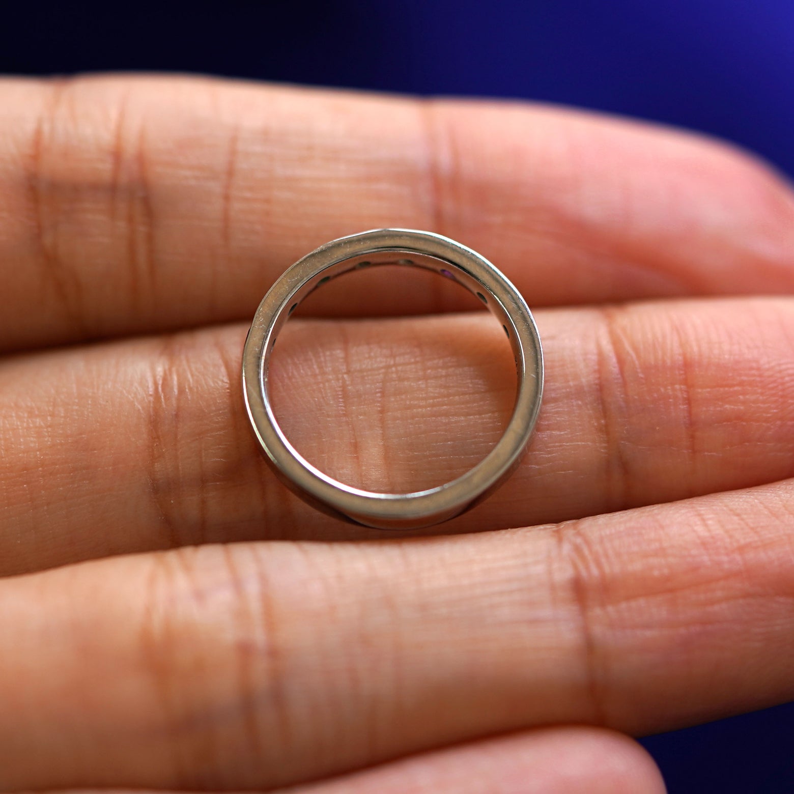 A white gold Rainbow Band in a model's hand showing the thickness of the band