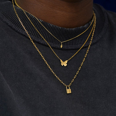 A model wearing solid 14k yellow gold Leaf, Butterfly, and Lock Necklaces layered