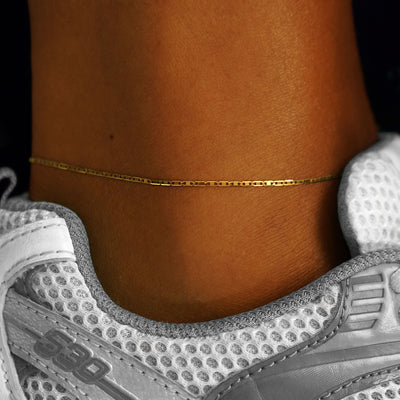 A models ankle wearing a 14k yellow gold Valentine Anklet