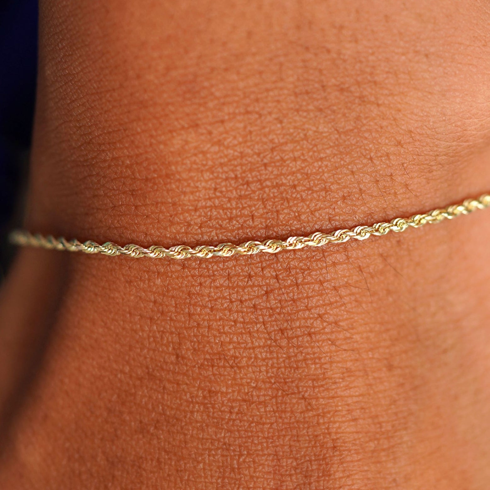 Close up view of a model's wrist wearing a solid 14k yellow gold Rope Bracelet