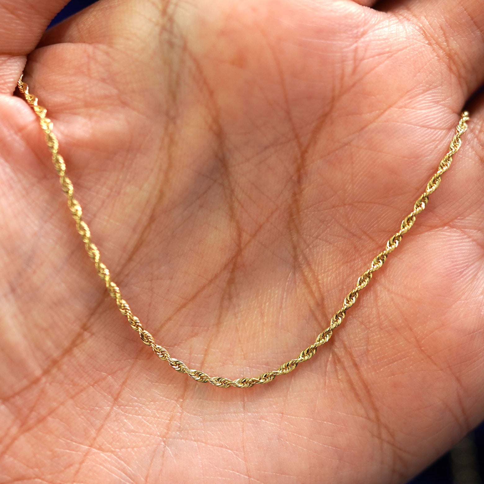A yellow gold Rope Bracelet draped on a model's palm