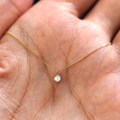 A solid 14k gold Rose Cut Diamond Necklace resting in a models palm