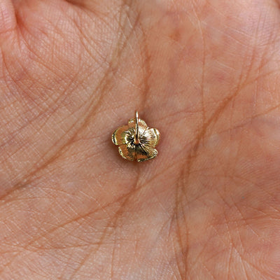 A 14k gold Rose Charm for chain resting in a model's palm to show the underside of the charm