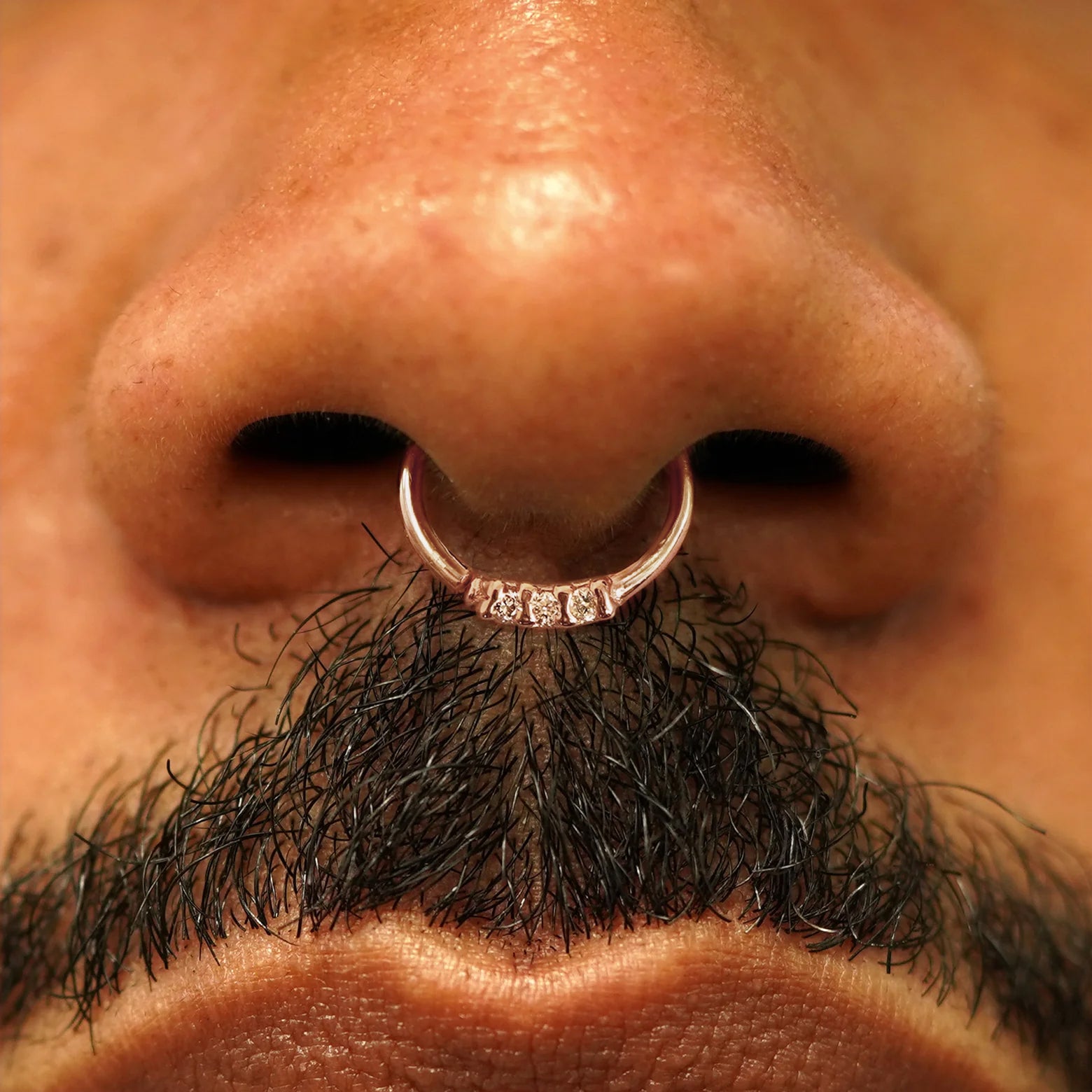 Close up view of a model's nose wearing a 14k rose gold 3 Diamond Septum