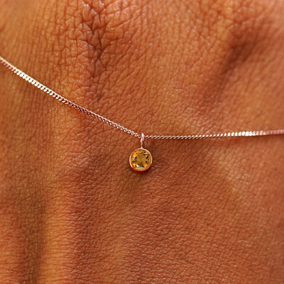 Close up view of a 14k rose gold Citrine Necklace draped across the back of a model's hand