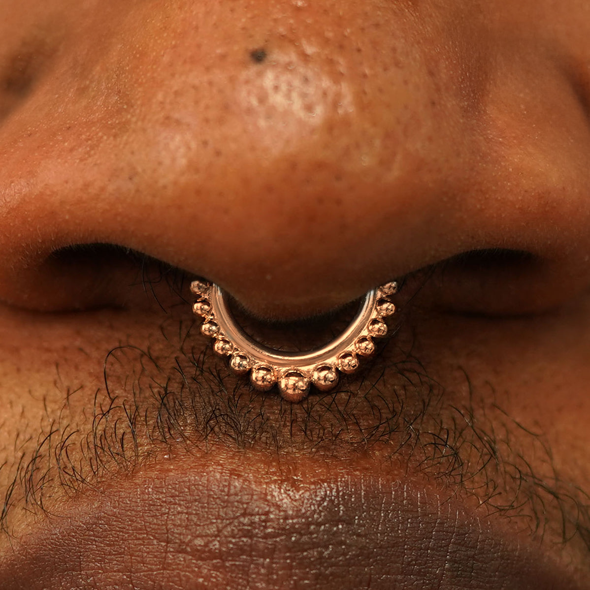 Close up view of a model's nose wearing a 14k rose gold Beaded Septum