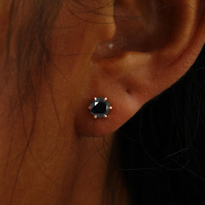 Close up view of a model's ear wearing a rose gold black 5mm Moissanite Earring