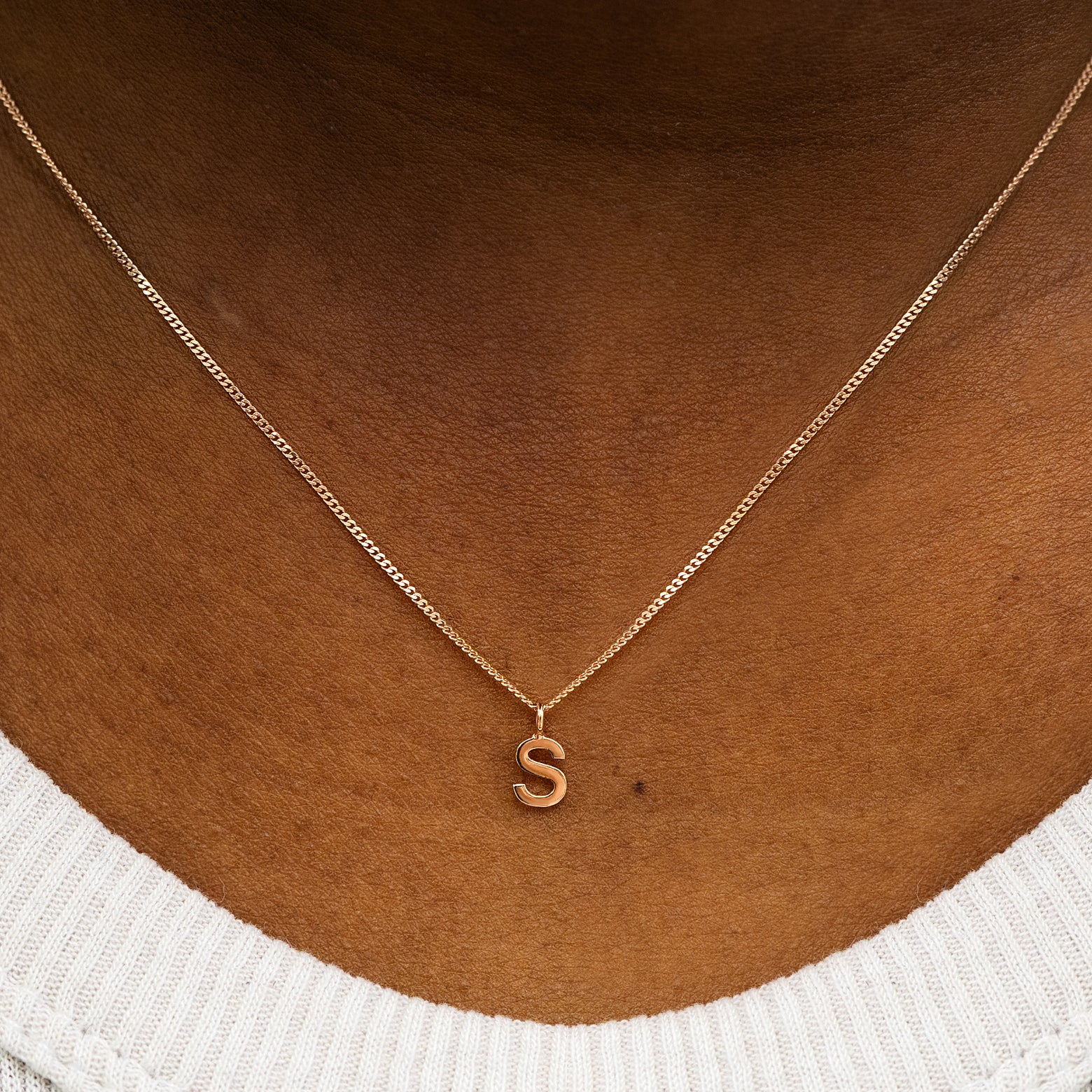 Close up view of a model's neck wearing a 14k solid rose gold Block Initial Charm Necklace in the letter S