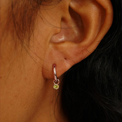 Close up view of a model's ear wearing a rose gold Champagne Diamond Charm on a Curvy Huggie Hoop