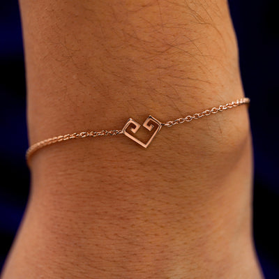 A close up view of a model's wrist wearing a rose gold Chere Heart Bracelet