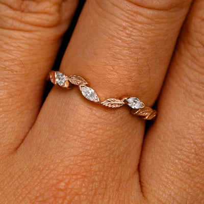 Close up view of a model's fingers wearing a 14k rose gold Chevron Leaves and Marquise Diamonds Band