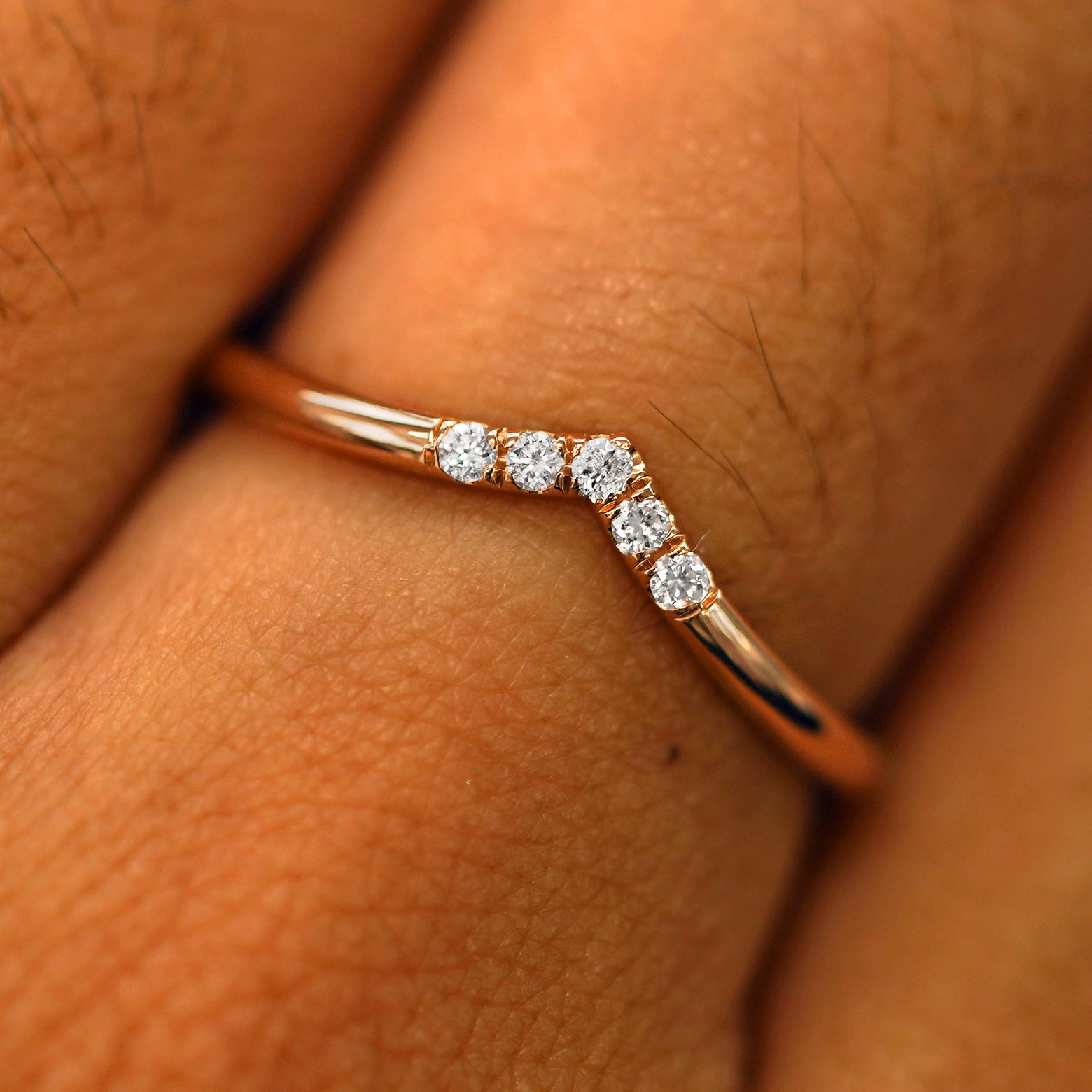 Close up view of a model's fingers wearing a 14k rose gold Diamond Chevron Band